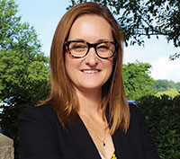 Professional woman wearing a blazer and eyeglasses smiling